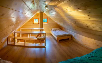 a large wooden cabin with a bed and a table at Wooden Chalet - Homestead Vrhovc in Železniki