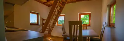 a room with a kitchen with a wooden table and some windows at Wooden Chalet - Homestead Vrhovc in Železniki