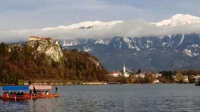 a group of people in a boat on a lake with mountains at Spacious apartment in Bled