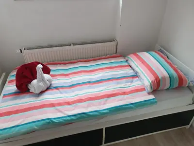 a stuffed animal sitting on a bed with a striped blanket at Apartma Alja Podkoren in Kranjska Gora