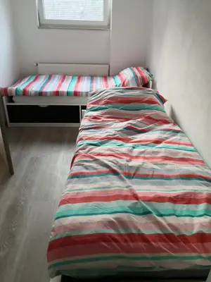 a bed with a striped comforter in a bedroom at Apartma Alja Podkoren in Kranjska Gora