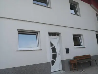a white building with a door and a bench at Apartma Alja Podkoren in Kranjska Gora
