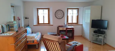 a living room with a tv and a desk and chairs at Apartment Perunika in Cerkno