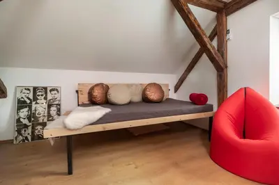 a bedroom with a bed and a red chair at LTE Apartments in Maribor