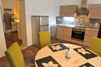 a kitchen with a wooden table and green chairs at Gostilna in Prenočišča Brančurnik in Prevalje