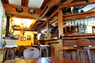 a restaurant with a wooden bar with wooden stools at Gostilna in Prenočišča Brančurnik in Prevalje