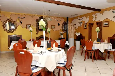 a dining room with white tables and chairs and a wall with maps at Gostilna in Prenočišča Brančurnik in Prevalje