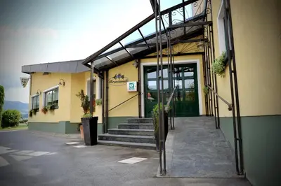 a building with a green door and stairs in front at Gostilna in Prenočišča Brančurnik in Prevalje