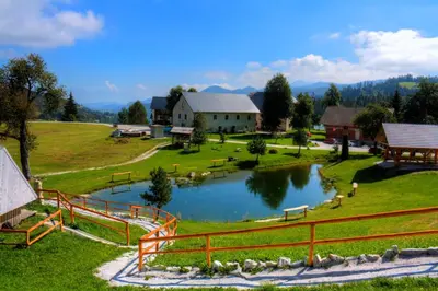 a view of a farm with a pond and a barn at Glamping Vrhovc in Železniki