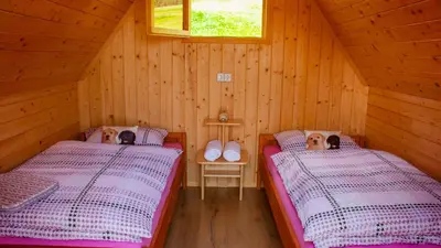 two beds in a room with wooden walls at Glamping Vrhovc in Železniki