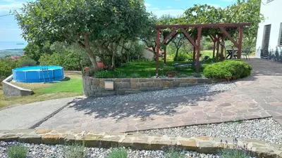 a garden with a stone wall and a gazebo at Apartma Nona Roža in Zgornje Škofije
