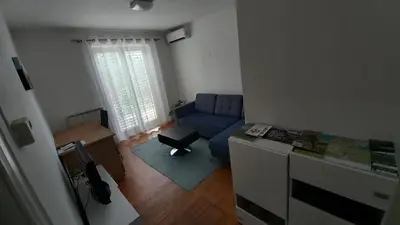 a living room with a blue couch and a table at Apartma Nona Roža in Zgornje Škofije