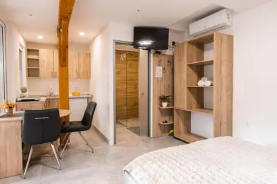 a bedroom with a bed and a desk and a kitchen at Apartmaji Natura KOLPA in Adlešiči