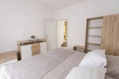 a white bedroom with a large bed and a kitchen at Apartmaji Natura KOLPA in Adlešiči
