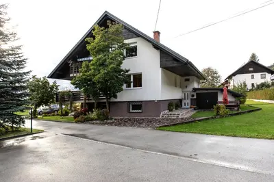a white house with a black roof on a street at Honey apartments in Žirovnica