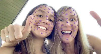 two girls holding up their faces with doughnuts on their faces at 18Home apartments, Mojstrana in Mojstrana
