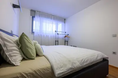 a bedroom with a bed with white sheets and a window at Sunrise Maribor apartment with private parking in Maribor