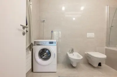 a bathroom with a washing machine and a toilet at Sunrise Maribor apartment with private parking in Maribor