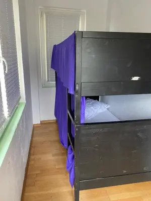a black bunk bed with purple sheets in a room at Travellers' Haven Hostel in Bled