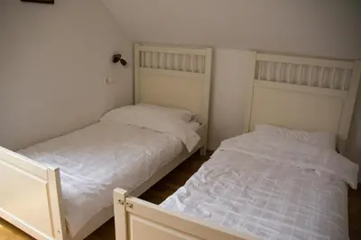 two beds in a bedroom with white sheets at Travellers' Haven Hostel in Bled