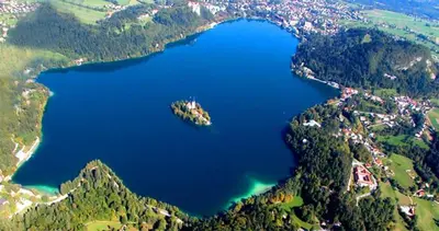 an aerial view of a large blue lake in the mountains at Apartments and Rooms Villa Vive in Bled