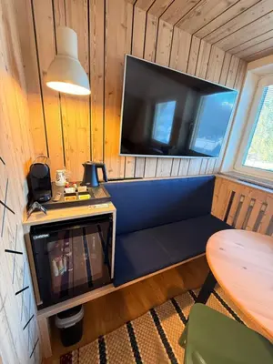 a room with a couch with a tv and a table at Na Vasi restavracija in prenočišča in Škofja Loka