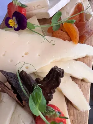a cutting board with cheese and vegetables on it at Na Vasi restavracija in prenočišča in Škofja Loka