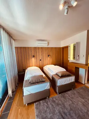 two beds in a room with wood paneling at Na Vasi restavracija in prenočišča in Škofja Loka