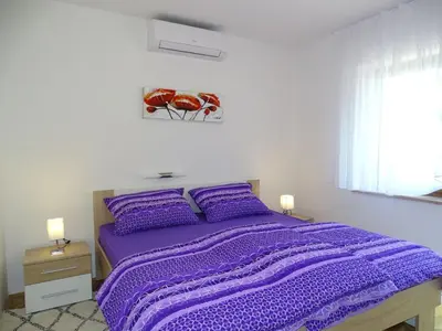a purple bed in a white bedroom with two lamps at Kolpa Paradise in Metlika