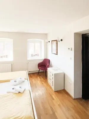 a bedroom with two beds and a red chair at Stairway to the castle in Ljubljana