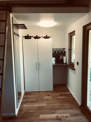 a kitchen with white cabinets and a wooden floor at Village Apartments in Šentilj