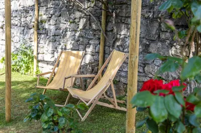 two chairs sitting in front of a stone wall at Domačija Mirko in Miren