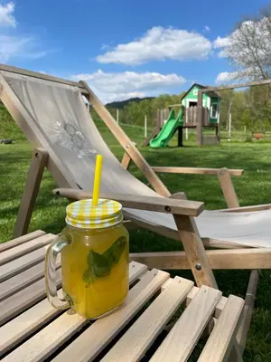 a jar of juice sitting on a bench next to a chair at Glamping PEC - HALFBOARD in Selnica ob Dravi
