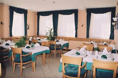 a dining room with tables and chairs and windows at Rooms Hochkraut in Celje