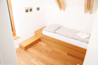 a small bedroom with a bed and a wooden floor at Apartment Jurijana - New 4-Bedroom Triplex with Sauna & Garden in Bohinj
