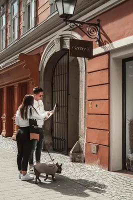 a woman and a man walking a dog on a street at Gentry11 Rooms&More in Maribor