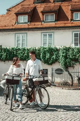 a man and a woman riding bikes down a street at Gentry11 Rooms&More in Maribor