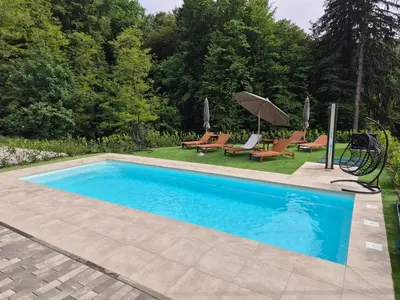a swimming pool with chairs and an umbrella at Villa de Roya in Rogaška Slatina
