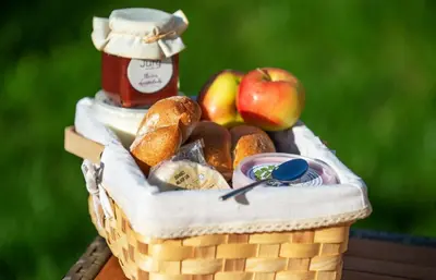 a basket of bread and apples and a jar of jam at Villa de Roya in Rogaška Slatina