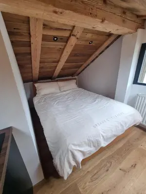 a bed in the corner of a room with wooden ceilings at Apartments Bedanc in Kranjska Gora