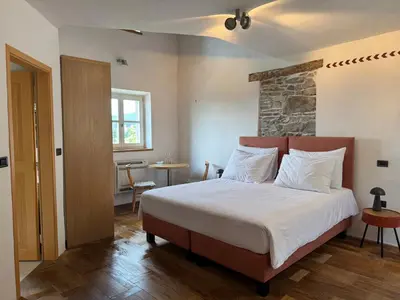a bedroom with a large bed with a stone wall at SMARTnoOK Rooms and Apartment in Šmartno