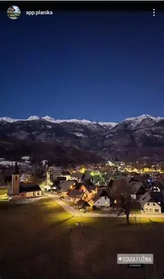 a view of a town at night with snow capped mountains at Apartment in the heart of nature in Bohinj