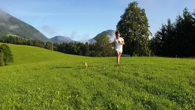 a person running in a field with a dog at Apartma Lesjak - pobeg v naravo in Mozirje