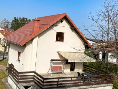 a house with a red roof and a chair on the porch at House Marin - whole house in Maribor