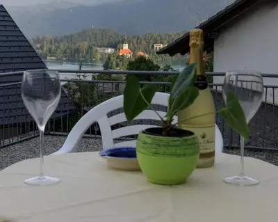 a table with a bottle of wine and two glasses at Apartment Mavrica Bled, quiet location, with a view of the lake in Bled