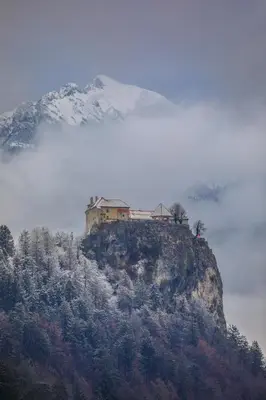a house on top of a mountain in the fog at Apartment Mavrica Bled, quiet location, with a view of the lake in Bled