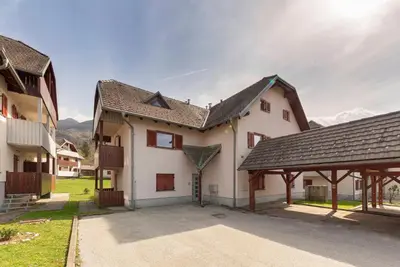 a large white house with a brown roof at Timber Apartment in Bohinj