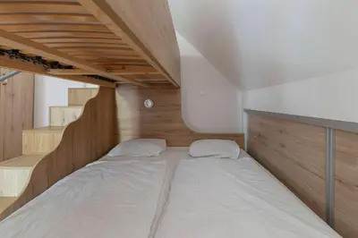 a bed in a small room with stairs at Timber Apartment in Bohinj