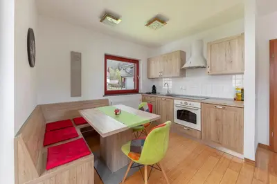 a kitchen with wooden cabinets and a table and chairs at Timber Apartment in Bohinj