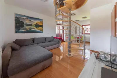 a living room with a couch and a spiral staircase at Timber Apartment in Bohinj
